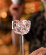 Close-up of a group of three friends standing at the bar talking and toast with glasses of beer and a cocktail in club bar