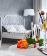 Makeup accessories lying on white round table in grey bedroom